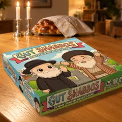 Gut Shabbos box on a Shabbos table beside candles and challah